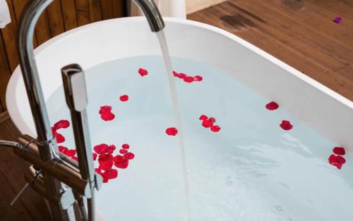 a tub filled with water with red flowers on the floor at 隐栖堂酒店 成都太古里合江亭店 in Chengdu
