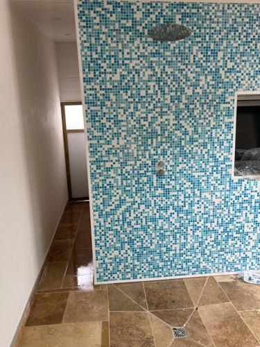 a bathroom with a blue tiled wall in a room at Logement thérapie bien-être in Pont-lʼAbbé
