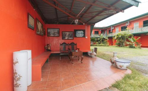 a room with a red wall with a bench and a table at Max Travellers Inn by RedDoorz in Lapu Lapu City