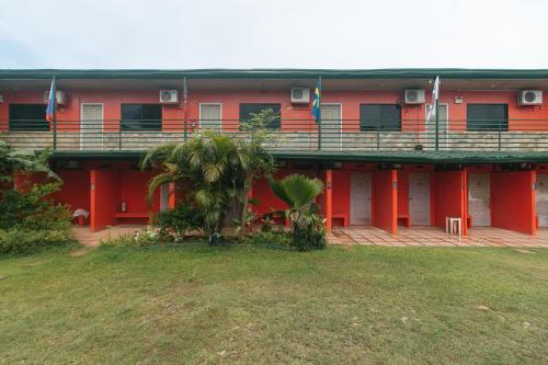 a red building with a balcony and palm trees at Max Travellers Inn by RedDoorz in Lapu Lapu City