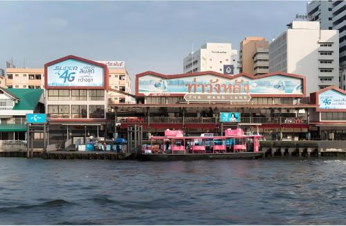 a boat is docked on the water in front of buildings at GO INN Siriraj BKK โกอินน์ ศิริราช in Bangkok Noi