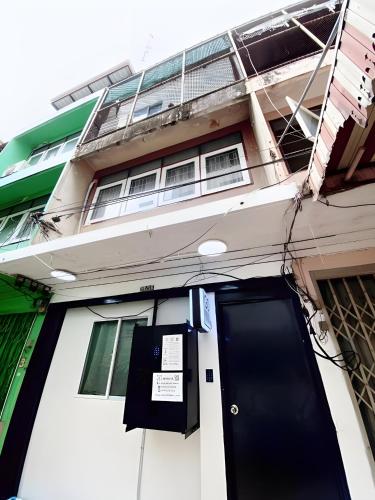 a building with a black door in front of it at GO INN Siriraj BKK โกอินน์ ศิริราช in Bangkok Noi