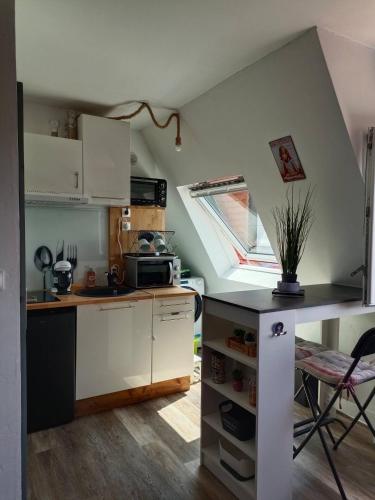 une cuisine avec des armoires blanches, une table et une fenêtre dans l'établissement Studio à 300 m de la plage à pied et des commerces, à Villers-sur-Mer