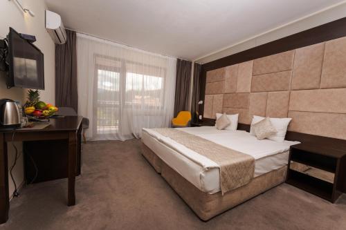a bedroom with a bed and a desk and a television at Family Hotel The View & SPA in Tsigov Chark