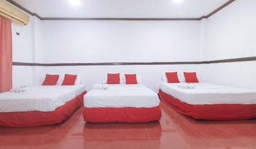two beds in a room with red and white pillows at Max Travellers Inn by RedDoorz in Lapu Lapu City