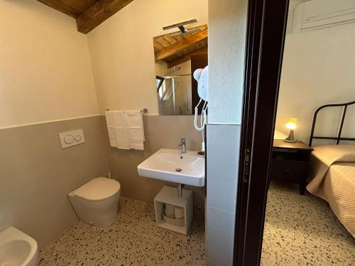 a bathroom with a sink and a toilet and a bed at Azienda Agrituristica Il Pago in Nova Siri Marina