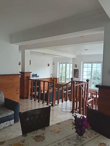 a living room with a table and chairs and windows at Havelock Inn in Nuwara Eliya