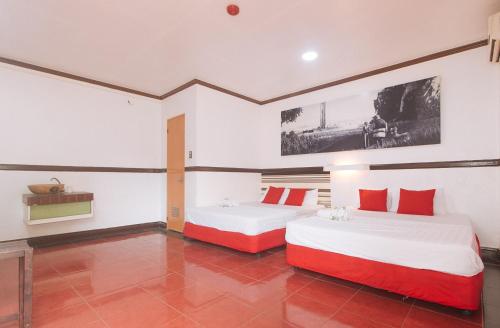 two beds in a room with red and white at Max Travellers Inn by RedDoorz in Lapu Lapu City