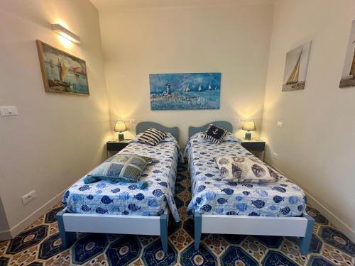 two twin beds in a room with two lamps at Villa Liliana - Casa Aurora - Trilocale Elegante con Balcone Vista Mare - Accesso Diretto alla Spiaggia in Varigotti