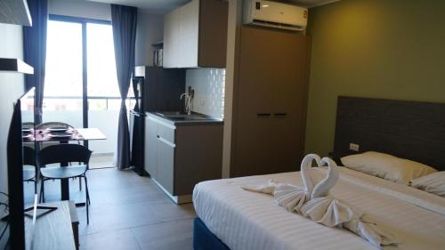 Un dormitorio con una cama y una mesa y una cocina. en Blue Edge Studio T3-527, en Ban Klang