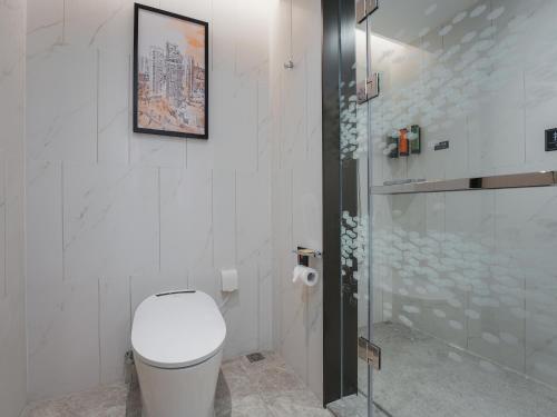 a white bathroom with a toilet and a shower at Hampton by Hilton Dongguan Fenggang in Dongguan
