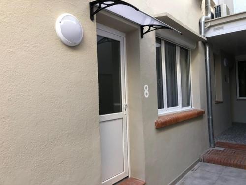 une porte d'un bâtiment avec une porte blanche et une fenêtre dans l'établissement Studio #8 climatisé à 10 min des plages, à Perpignan