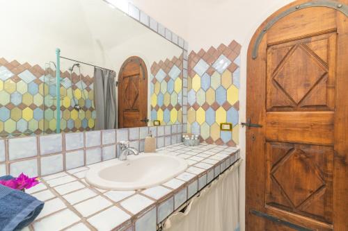a bathroom with a sink and a wooden door at Villa Ginepro con Piscina Privata in San Teodoro