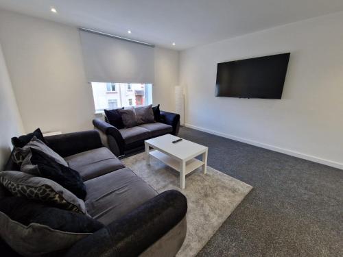 a living room with a couch and a tv at Modern 2 Bedroom with extra Loft Bedroom in Glasgow