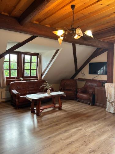 a living room with leather furniture and a table at Wellness hotel & minipivovar Kněžínek in České Budějovice