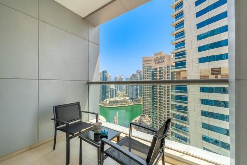 a balcony with two chairs and a large window at Cityscape & Coastal Charm Elegant 2br Seaside in Dubai Marina