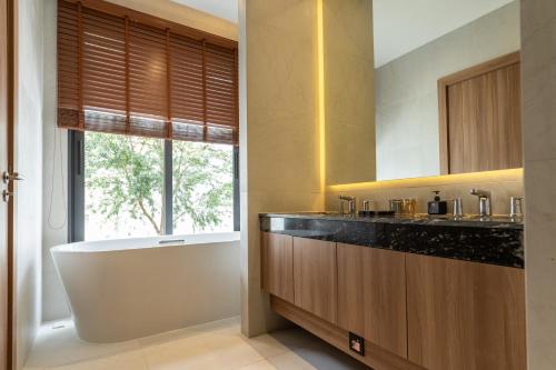 a bathroom with a bath tub and a window at Mouana Breeze Mai Khao 4-bedroom Pool Villa 9919 in Mai Khao Beach