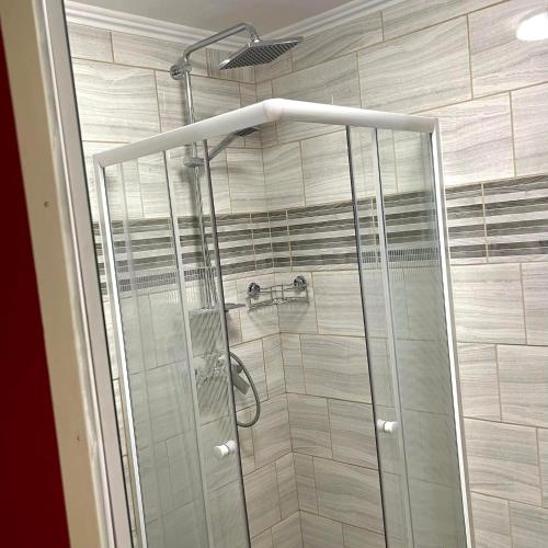a shower with a glass door in a bathroom at Apartmanház - Delta Kemping in Balatonederics