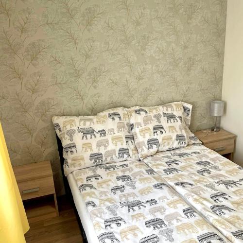 a bed in a bedroom with a bedspread and pillows at Apartmanház - Delta Kemping in Balatonederics
