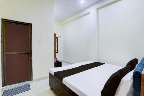 a bedroom with a white bed and a door at Collection O Sudhirpur near Phonix Hospital in Varanasi