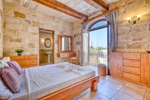 a bedroom with a bed and a bathroom with a window at New to the market - Unique house with pool by SF Homes in Għargħur