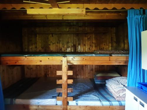 ein Etagenbett aus Holz mit blauen Vorhängen in der Unterkunft Gscheidegger Hütte in Johnsbach