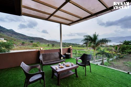 a patio with chairs and a table on the grass at Villa Veya By VEO - Part Of StayVista in Satara