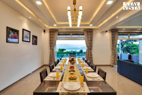 a long dining room with a long table and chairs at Villa Veya By VEO - Part Of StayVista in Satara