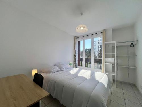 une chambre blanche avec un lit et une fenêtre dans l'établissement Beau T3 avec balcon à Perpignan, à Perpignan