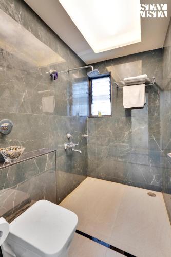 a bathroom with a toilet and a glass shower at Villa Veya By VEO - Part Of StayVista in Satara