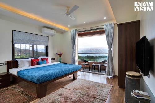 a bedroom with a bed and a large window at Villa Veya By VEO - Part Of StayVista in Satara