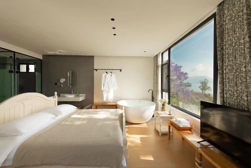 a bedroom with a tub and a large window at Dali Blue House Sea View B&B in Dali Ancient Town