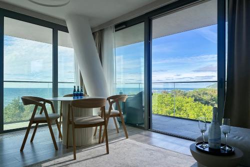 a dining room with a table and chairs and windows at Privilege Apartment in Międzyzdroje