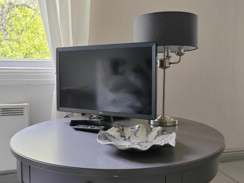 a computer monitor on a table with a lamp and a remote at Väentupa in Kaarina