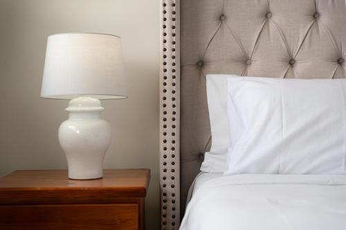a white lamp on a nightstand next to a bed at Austral Spacious large 5 br home with Central AC in Austral