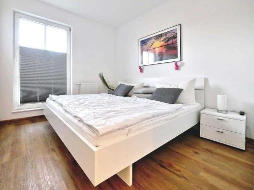 a large white bed in a white room with a window at Ferienpark Scharmützelsee in Wendisch Rietz