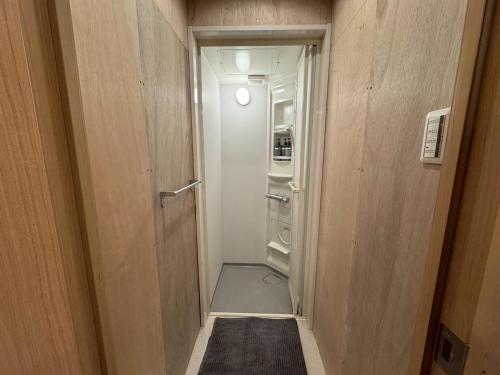 a small hallway with an open door to a refrigerator at 石垣ゲストハウスオハナ in Ishigaki Island