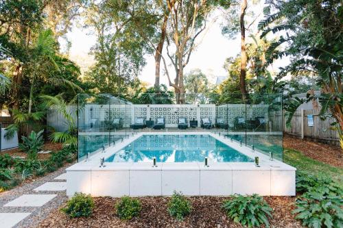a swimming pool with a glass wall around it at The Cottage at Pearl Beach in Pearl Beach