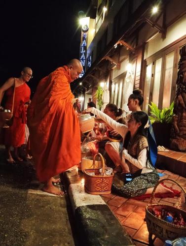 a man in an orange robe standing next to a group of people at Salana Boutique Hotel in Vientiane