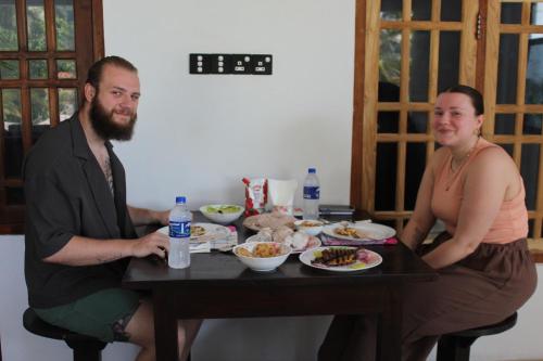 a man and a woman sitting at a table with food at Clara's Beach Inn in Trincomalee
