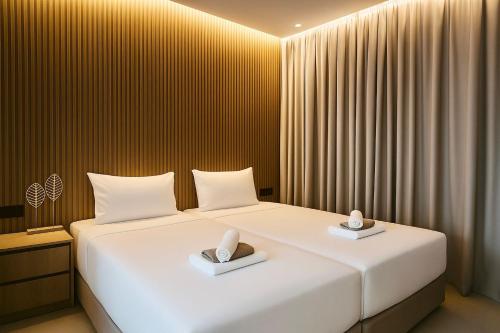 a bedroom with a large white bed with two pillows at NÓA Rooms - Adults Only in Ayia Napa