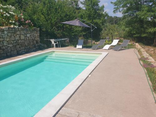 - une piscine avec des chaises, une table et un parasol dans l'établissement chez Marcel, à Rosières