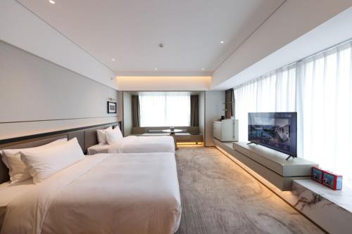 a hotel room with two beds and a flat screen tv at Ramada by Wyndham Foshan Danzao in Huadu
