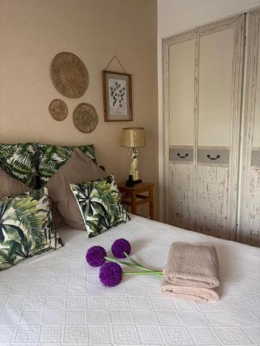 a bed with purple flowers on top of it at Chambre Bohème chic avec jacuzzi in Liouc