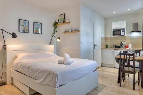 Cet appartement comprend une chambre avec un lit blanc et une cuisine. dans l'établissement Anne studio tout équipé à proximité de la gare et du centre-ville, à Rouen