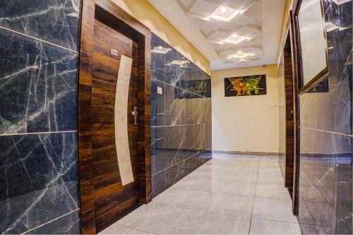 a hallway with a wooden door and tile walls at FabHotel Brij Residency - hoshangabad , Near barkatullah university in Naiāpura