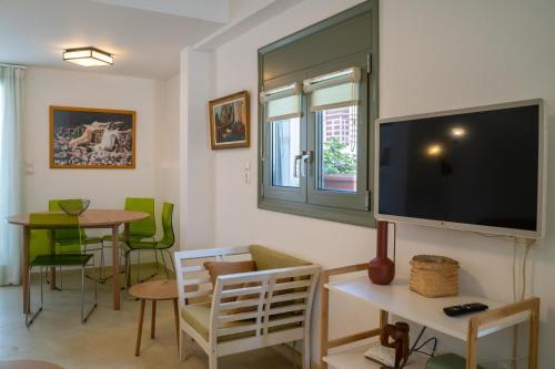 Una sala de estar con un televisor de pantalla plana en la pared. en Eclectic Urban Nest, en Heraklion