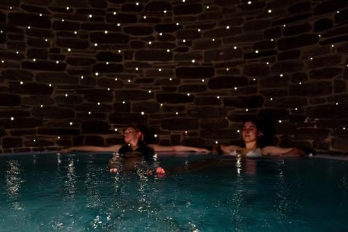 two women laying in a swimming pool at night at Rugard Thermal Strandhotel in Binz