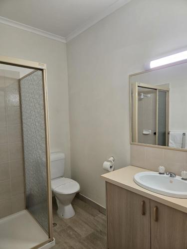 a bathroom with a toilet and a sink and a mirror at KooWeeRup Motel in Koo-Wee-Rup