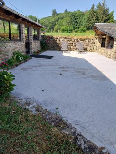 une allée avec deux chaises devant un bâtiment en pierre dans l'établissement La Bergerie Maison familiale, à La Salvetat-sur-Agout